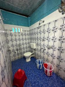 a bathroom with a toilet and a blue tiled floor at DOHIKOTORA Eco Camp, Resort & Restaurant in Narjon Basti