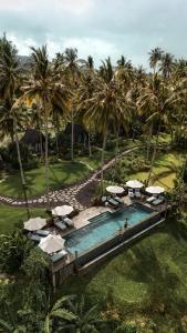 an aerial view of a resort with a pool and palm trees at Desa Cabins in Balian