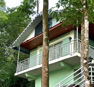 a building with a balcony in the middle of trees at Sukhim Farmstay in Mirik