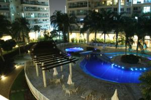 um grupo de bancos e uma piscina à noite em Le Parc Residential Resort no Rio de Janeiro