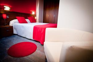 a bedroom with two beds with red pillows and a couch at Apartamentos Abaco in Llanes
