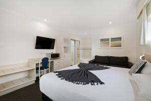 a white bedroom with a bed and a couch at Comfort Inn All Seasons in Ballina