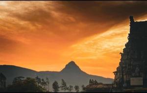 a sunset with a view of a building and a mountain at Dilani Adamspeak RiverStay in Nallathanniya