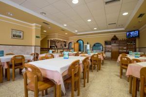 ポルトノボにあるHostal O Camoucoのピンクのテーブルクロスが敷かれたテーブルと椅子が備わるレストラン