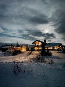 a large house in the snow with lights on at Log Cabin Near Høgevarde With Mountain Views in Granheim
