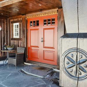 an orange front door of a house with a table at Log Cabin Near Høgevarde With Mountain Views in Granheim