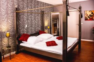 a bedroom with a four poster bed with red pillows at Hotel SleepInn Volkspark in Hamburg