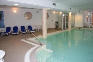 una gran piscina con sillas azules en una habitación en Hotel Olimpic, en Baselga di Pinè