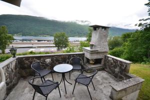 a patio with a table and chairs and a fireplace at Villa Haudalan Åndalsnes in Åndalsnes