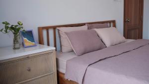 a bed with white pillows and a vase on a dresser at MayHome Binh Dinh in An Hòa +29 photos