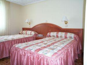 two beds in a hotel room with pink sheets at Hotel Buenos Aires in Villafría de Burgos