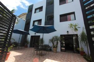 a patio with tables and umbrellas in front of a building at Hotel Los Girasoles in Cancún