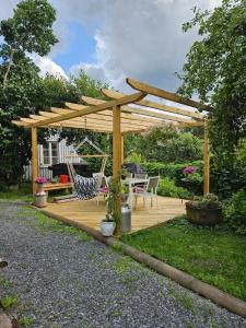 a wooden pergola in a garden with a table and chairs at Guesthouse Onnia, kattohuoneisto Siurossa in Siuro