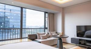 a room with a large window with a couch and a tv at Shenzhen Cloud Park Manhattan Hotel in Tiantangwei