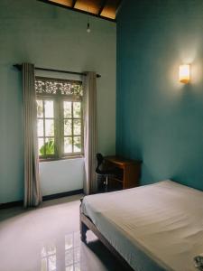 a bedroom with a bed and a window and a desk at Sunset Mirage Villa in Unawatuna