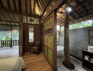 a room with a bed and a bathroom with a tree at The Manikyang Residence in Tabanan