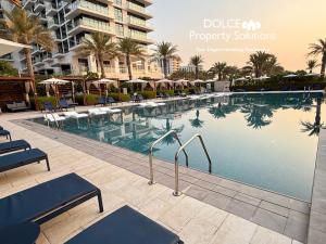 a swimming pool at a resort with chairs and umbrellas at Address Beach Resort Residences Bahrain in Manama +37 photos