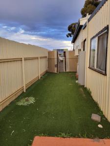 une cour avec une clôture et de l'herbe verte dans l'établissement Corella Accommodation 1E, à Boulder