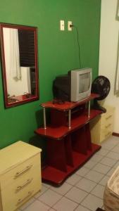 a room with a tv and a green wall at Larus 107 in Florianópolis