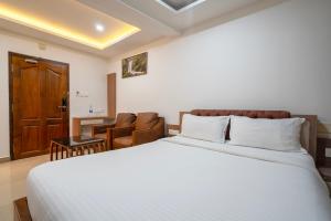 Un dormitorio con una cama grande con sábanas blancas. en Hotel Staymax Trend kannur, en Kannur