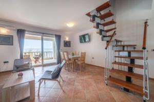 a living room with a spiral staircase and a table and chairs at Seaside Apartment Barić Draga in Barić Draga