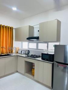 a kitchen with white cabinets and a stove top oven at Celestial Negombo Resort Villa 10 in Negombo