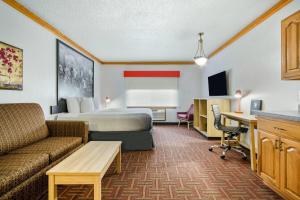 a hotel room with a bed a couch and a desk at Super 8 by Wyndham Eveleth in Eveleth