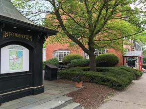 een zwart gebouw met een bord voor een boom bij The Tunnicliff Inn in Cooperstown