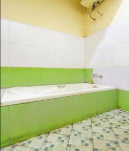 a green and white bathroom with a bath tub at GRIYA HARMONI Homestay Jogja in Adi Sutjipto