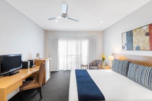 a bedroom with a bed and a desk and a tv at Oaks Broome Hotel in Broome