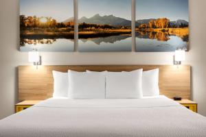 a bedroom with a bed with four paintings on the wall at Days Inn by Wyndham Worland in Worland +74 photos