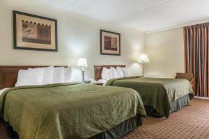 twee bedden in een hotelkamer met groene lakens bij Rodeway Inn Brookville in Brookville +25 foto's