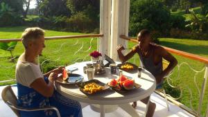 a man and a woman sitting at a table with food at Egg Botanical View in Entebbe