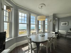 a dining room with a table and chairs and windows at The Eastleigh in Seaton