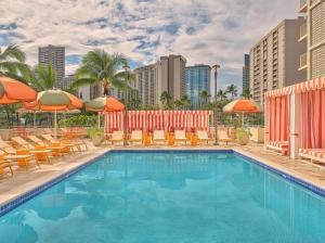 een zwembad met stoelen en parasols bij The Ambassador of Waikiki, Tapestry Collection by Hilton in Honolulu