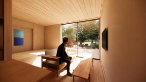 a man sitting in a chair in a room with a window at GEOSPOT Motohakone A in Hakone