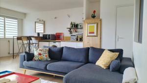 a blue couch in a living room with a kitchen at Parking gratuit, garage vélo privatif, proche tramway in Rezé