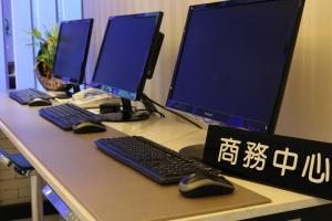 a desk with three computer monitors and a keyboard and mouse at J-HOTEL in Kaohsiung +54 photos