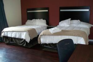 two beds sitting next to each other in a hotel room at Budget Inn & Suites in Wall Township