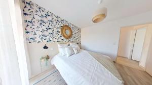 a bedroom with a bed with white sheets and a floral wall at Le Cocon d'Andernos Rooftop et Sea View in Andernos-les-Bains