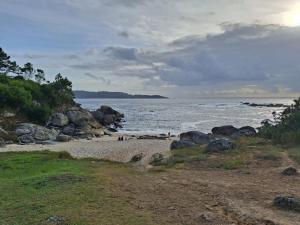 a beach with people on the sand and the water at Espe Daga Apartamento in Bueu
