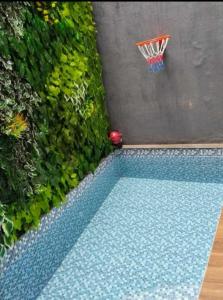 a pool with a basketball hoop next to a green hedge at Villa Artha Asia Hills in Batu