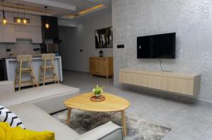 a living room with a couch and a tv and a table at Serene Apartments in Kigali