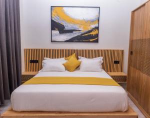a bedroom with a large bed with yellow and white pillows at Serene Apartments in Kigali