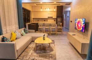 a living room with a couch and a table and a kitchen at Serene Apartments in Kigali