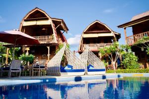 a resort with a swimming pool with chairs and umbrellas at Alain rooms AMED in Amed