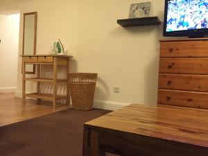 a living room with a dresser and a flat screen tv at The Tudors Three Bedroom Apartment in St. Albans