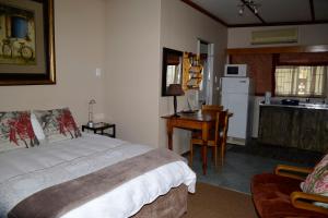 a bedroom with a bed and a desk and a kitchen at Marnicus B&B in Odendaalsrus