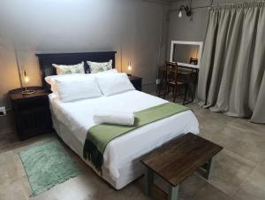 a bedroom with a large bed with a wooden table at La Mouna 4 in Bultfontein in Bultfontein