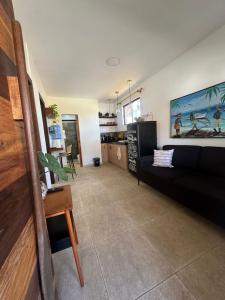 a living room with a black couch and a kitchen at Casa Praia - Recanto Tucuns Beira-Mar in Búzios +23 photos